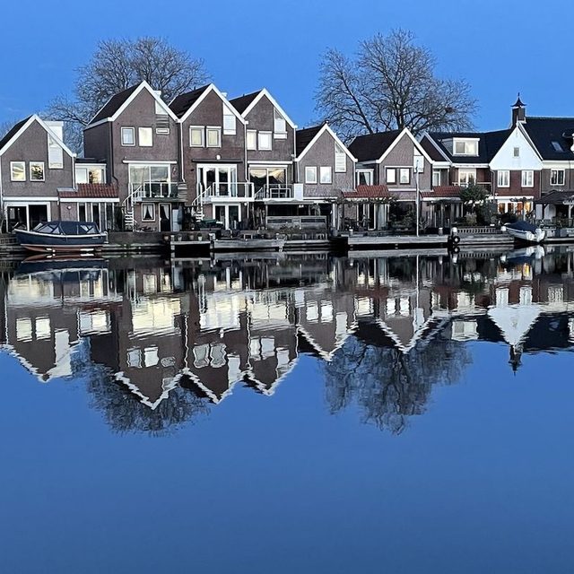 Brick houses and the Wilhelmina warehouse reflected in the Zaan at dusk