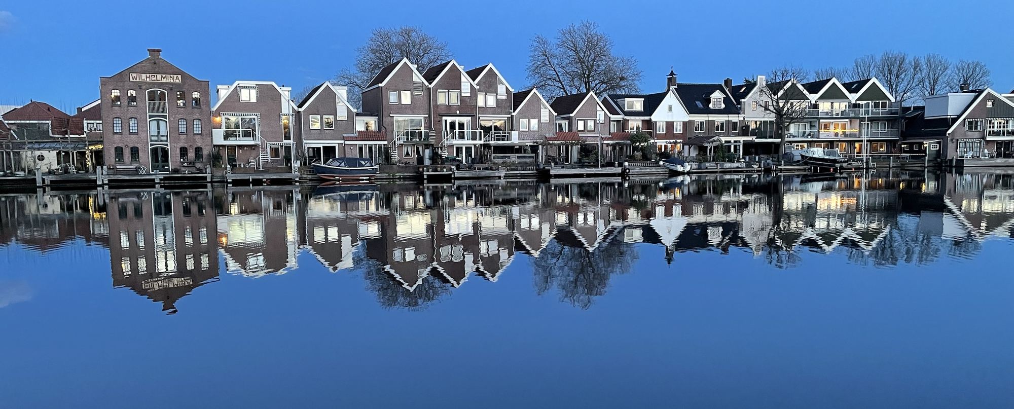 Brick houses and the Wilhelmina warehouse reflected in the Zaan at dusk